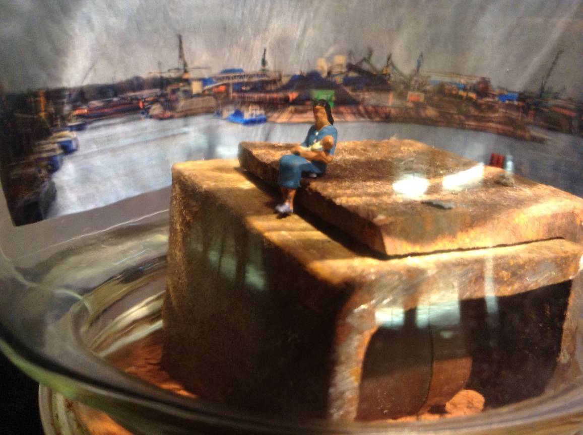 Eine junge Mutter sitzt allein mit ihrem Baby am Hafen.