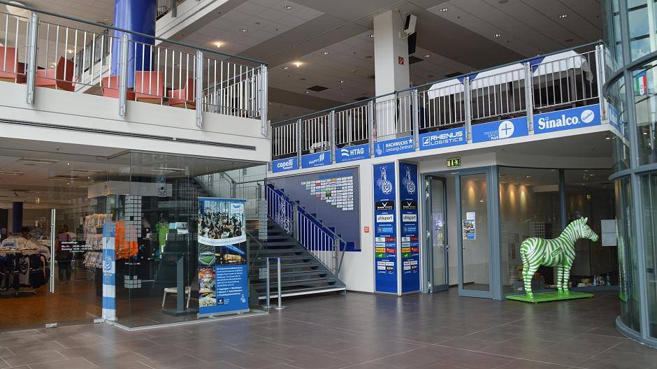 Links der Fanshop, die Treppe führt zum Businessbereich, die Türe neben dem Zebra zum...