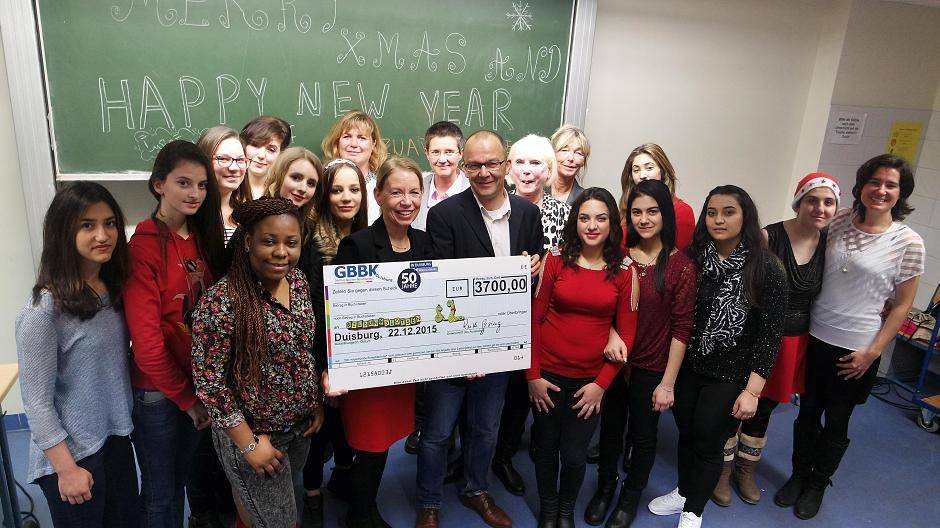 Im Rahmen einer Weihnachtsfeier einer Internationalen Vorbereitungsklasse des GBBK überreichte Ruth Gesing (Leiterin des Gertrud-Bäumer-Berufskolleg) die Spende an Klaus Peter Müller von den Bildungslotsen für Duisburg e.V.