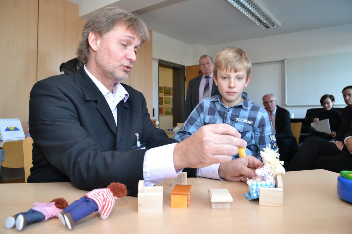  Dr. Guido Wolf, Oberarzt des SPZ erzählt Nico eine Geschichte um „Sally und Ann“. Was so einfach aussieht, ist im diagnostischen Bereich eine Möglichkeit, heraus zu finden, ob ein Kind möglicherweise autistisch ist oder nicht. 