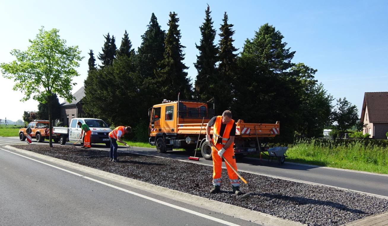 Mitarbeiter des Baubetriebshofs des Kreises Viersen stellen in Ziegelheide zur Aussaat von Wildblumensamen einen speziellen Substrat-Schotter-Untergrund her.