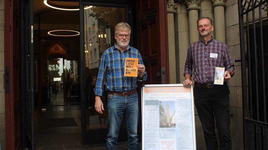  Am Portal St. Dionysius: Bernd Kaesmacher (l.) und Ulrich Hagens laden zum Programm der Sommerkirche ein. 