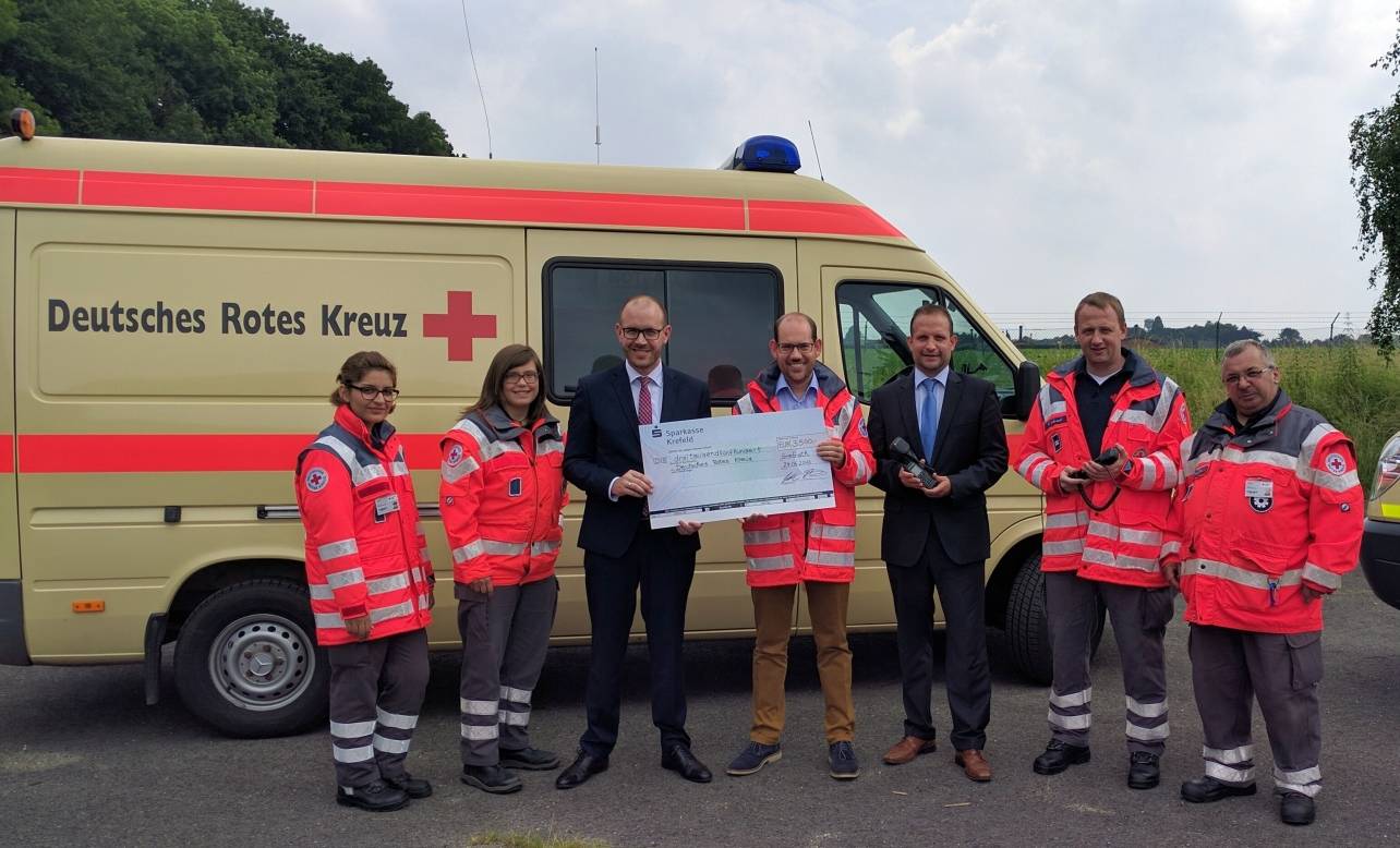 Christian Kappenhagen (Vorsitzender DRK, Bildmitte) freut sich über die Spende der Sparkasse, überreicht von Florian Deimel (3.v.l.) und Marco Jütten (Regionalmarktleiter, 5.v.l.).