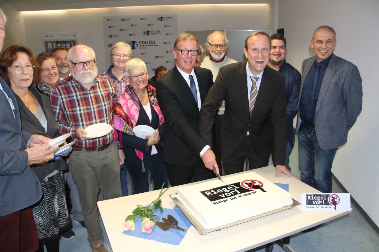 Polizeichef Rainer Furth und Thorsten Hansen (Gesellschaft Bürger und Polizei) schneiden die Zeugen-Café-Torte an.