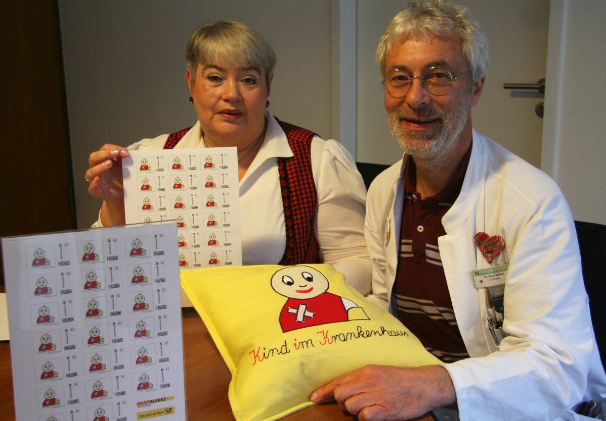  Monika Scharmach, Vorstandsvorsitzende von KiK, und Dr. med. Peter Seiffert, Chefarzt der Kinder- und Jugendklinik HELIOS St. Johannes Klinik, präsentieren die limitierte KiK-Briefmarke, die ab sofort lieferbar ist. 