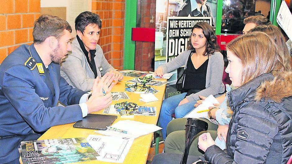 Oberleutnant Norwin Sommerfeld (in Uniform) erklärt Lina Günter (hinten rechts) und ihren Schulkameraden am ersten Berufsfindungsinformationsabend des Erasmus-von-Rotterdam-Gymnasiums in Viersen die zahlreichen Berufsmöglichkeiten in der Bundeswehr.
