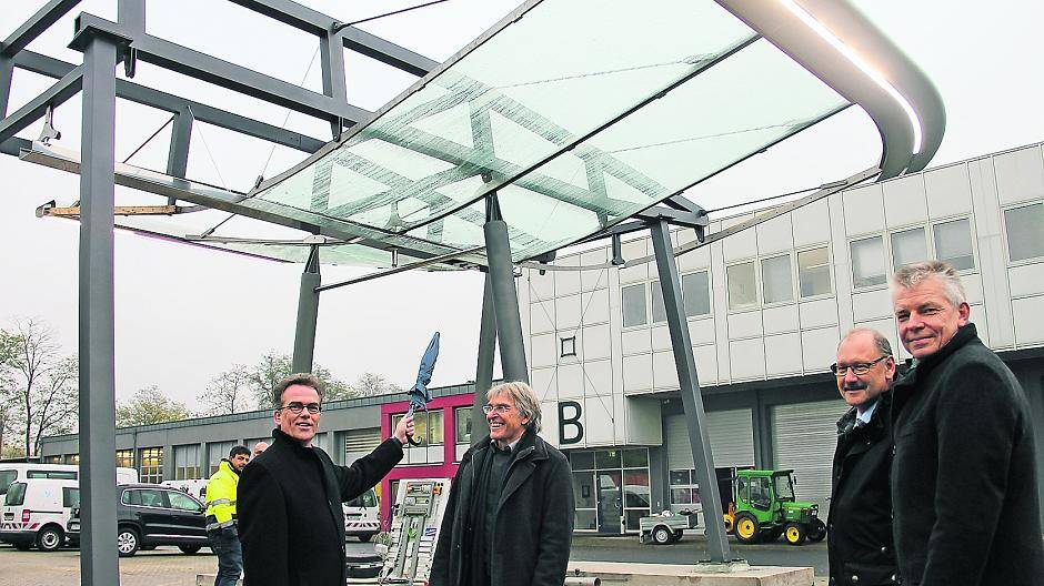  Der Teil steht für das Ganze: Bald braucht OB Gregor Kathstede (l.) keinen Schirm mehr, wenn vom Sommer 2015 an die neue Glasanlage die Ostwall-Haltestelle überdacht. Am Vorführmodell auf dem SWK-Gelände erfreuen sich Architekt Gerd Gröschl (Mitte), Baudezernent Martin Linne (r.) und Burkhard Kuphal (2.v.r.) von der SWK. Das Modell beglaubigt, dass alle Bauteile wirklich passen. 