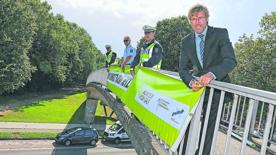 Die Fußgängerbrücke über der Korschenbroicher Straße ist einer von mehreren Orten in der Stadt, wo die Polizei jetzt Banner zum Thema Handynutzung am Steuer aufgehängt hat. Polizeipräsident Mathis Wiesselmann legte gemeinsam mit Kollegen der Verkehrsunfallprävention und der Direktion Verkehr selbst Hand an.