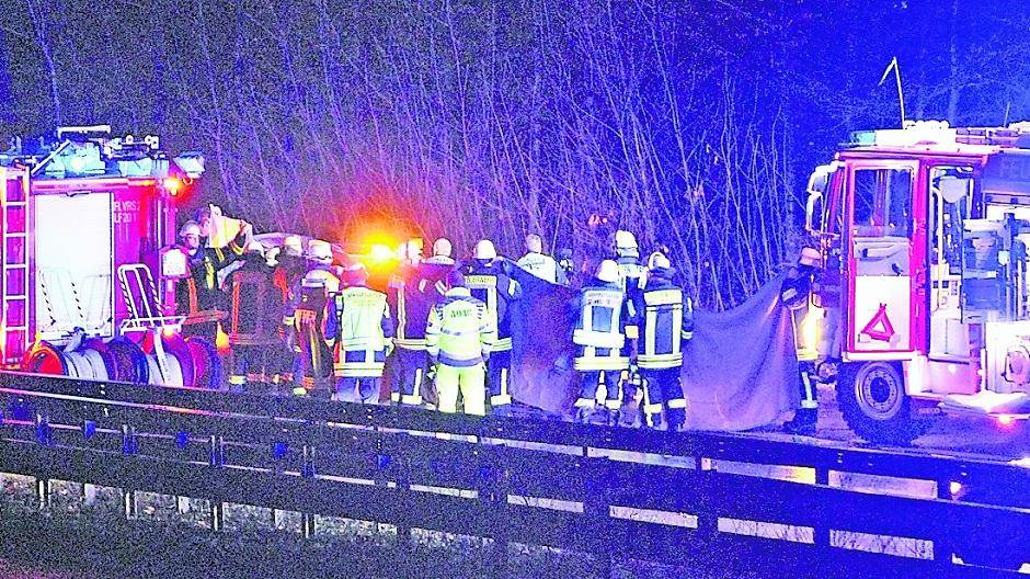  Feuerwehrmänner halten am Unfallort eine Decke hoch. Damit verhindern sie — aus Respekt vor den Opfern — den Blick auf die Unfallstelle. 