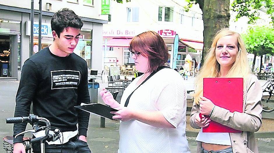 Vanessa Hommen und Sandra Kessels vom Fachseminar Altenpflege befragen in der Viersener Fußgängerzone einen jungen Mann zum Thema Demenz.