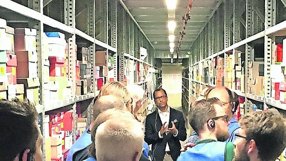 Dominic Jefferson (hinten) erklärt den Besuchern in einem Regalgang das Ordnungsprinzip bei Zalando. Ankommende Ware wird eingelagert, wo Platz ist. Über Mini-Chips auf jedem Artikel wird sie wiedergefunden.