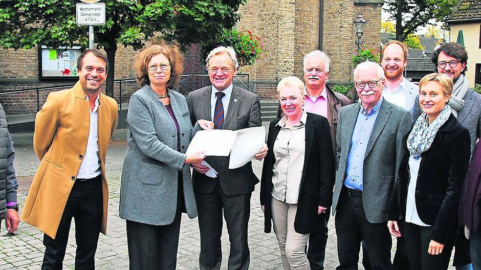  Regierungspräsidentin Anne Lütkes (3.v.l.) überreicht Bürgermeister Josef Heyes den Förderbescheid in Anwesenheit von Mitgliedern des Stadtrats, der Stadtverwaltung sowie von der „Stadtschmiede“ und dem Planungsbüro „Kraft.raum“. 
