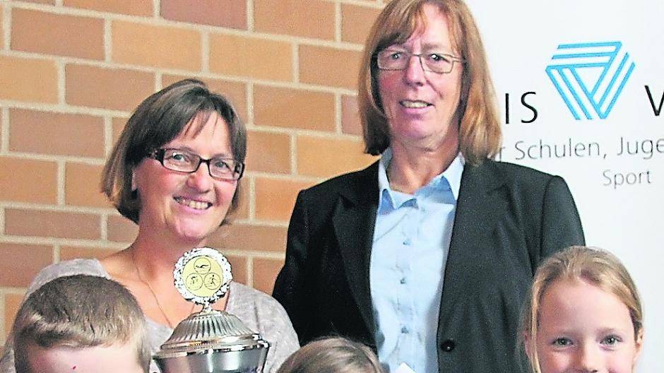  Leandro, Vera und Carla (v.l.) von der Astrid-Lindgren-Schule in Schiefbahn nehmen den Rolf-Richter-Wanderpokal für die erfolgreichste Schule im Sportabzeichen-Wettbewerb entgegen. Angelika Feller, Vorsitzende des Kreissportbund Viersen, gratuliert Sportlehrerin Silke Hohlstein-Terwesten. 