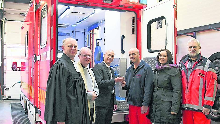 Thomas Heil (3.v.l.), Dezernent für den Bevölkerungsschutz beim Kreis Viersen, übergibt die Schlüssel für den neuen Rettungswagen der Wache in Heyen an Rettungsassisten Ralf Wälbers (4.v.l.). Pfarrer Bernd Mackscheidt (l.) von der Evangelischen Kirchengemeinde Brüggen/Elmpt und Pfarrer Wolfram Weihrauch von der Katholischen Pfarrkirche Niederkrüchten (2.v.l.) hatten das Fahrzeug gesegnet. Juliane Leewen (2.v.r.) vom Bevölkerungsschutz Kreis Viersen und Michael Botterbrodt (r.), ärztlicher Leiter für den Notarztstandort, warfen einen Blick ins neue Fahrzeug.