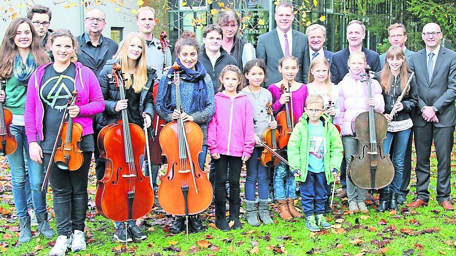 Musikschülerinnen und -schüler des St.-Bernhard-Gymnasiums postieren sich im weitläufigen Schulpark mit den Verantwortlichen der Kooperationsvereinbarung „Musikschulzentrum“ (hinten v.r.): Patrick Hofmacher (Malteser Werke), stellv. Schulleiter Andreas Päßler, Kreismusikschulleiter Ralf Holtschneider, Bürgermeister Josef Heyes, Kulturdezernent Dr. Andreas Coenen, die Musiklehrer Horst Jansen, Matthias Doffek, Florian Fleischmann und Hans-Michael Dücker. 