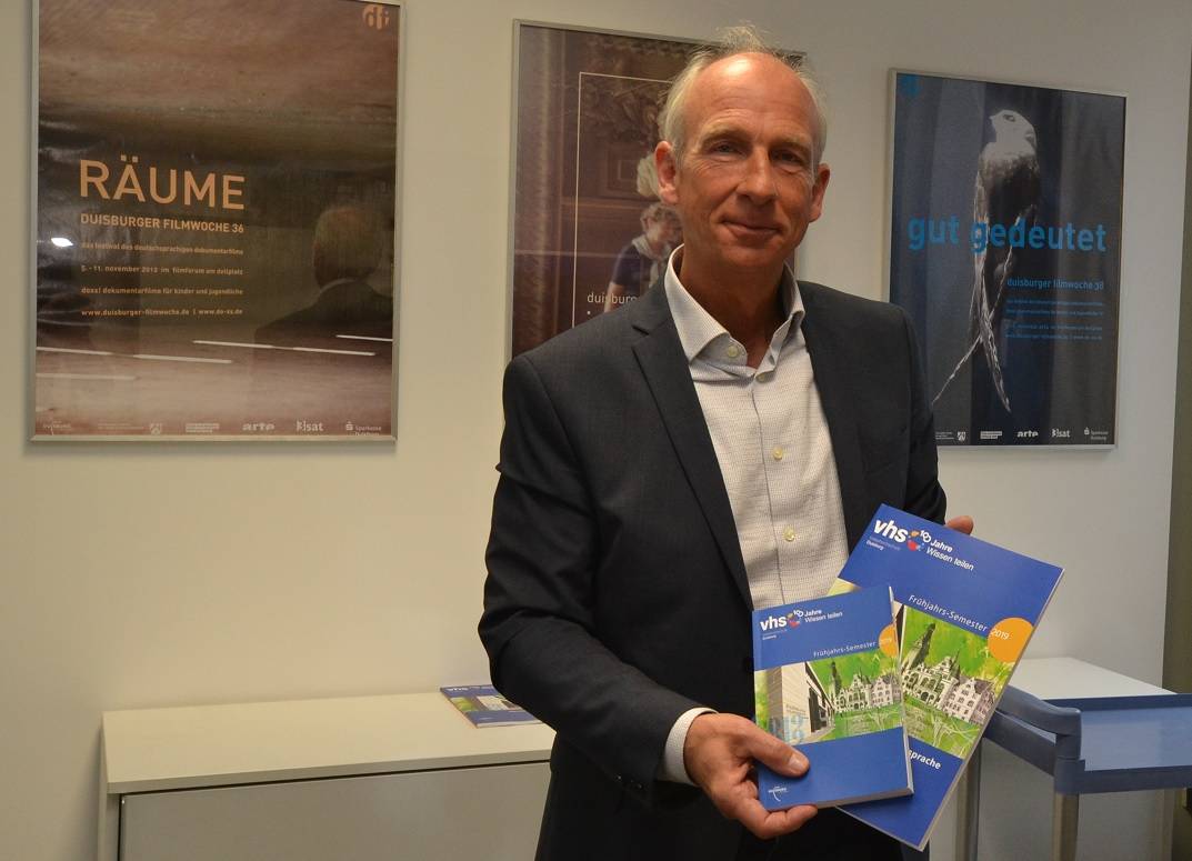  (Wissens-)Räume, gut gedeutet: Volker Heckner mit dem Vhs-Frühjahrsprogramm vor Plakaten der letzten Duisburger Filmwochen. 
