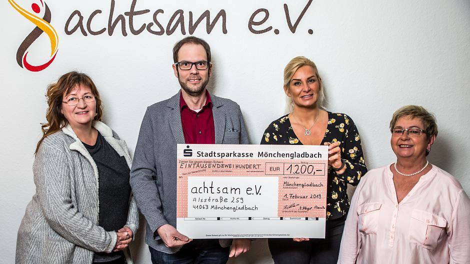  Andrea Dreimüller (l.), Benedikt Roemer und Maria Klingel (r.) übergeben den Scheck an Sandra Becker-Weber vom Verein achtsam e.V. 