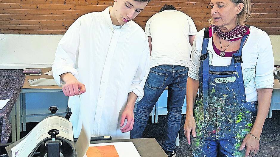 Ulrike Mayer-Trede probiert mit Jonathan Schassan unterschiedliche Techniken an der Druckpresse aus.