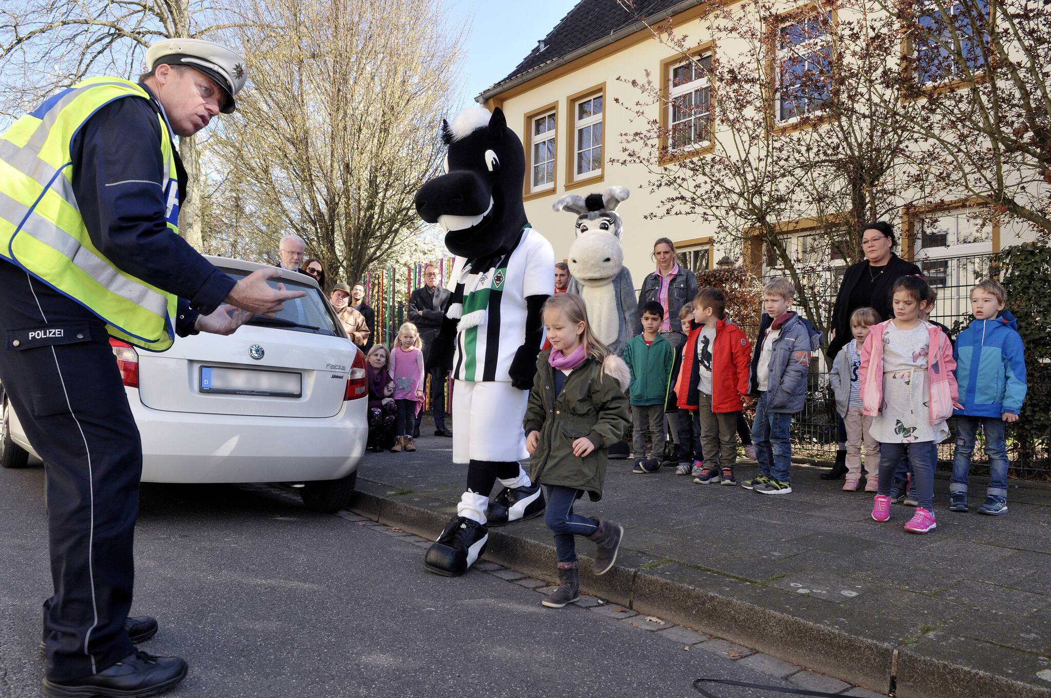 „Immer schön nach links und rechts schauen“: Verkehrssicherheitsberater Kalle Ditges erklärt den zukünftigen Schulkindern der Kita „Villa Sonnenschein“, was im Straßenverkehr zu beachten ist. Auch Jünter und Goldi sind aufmerksam bei der Sache.