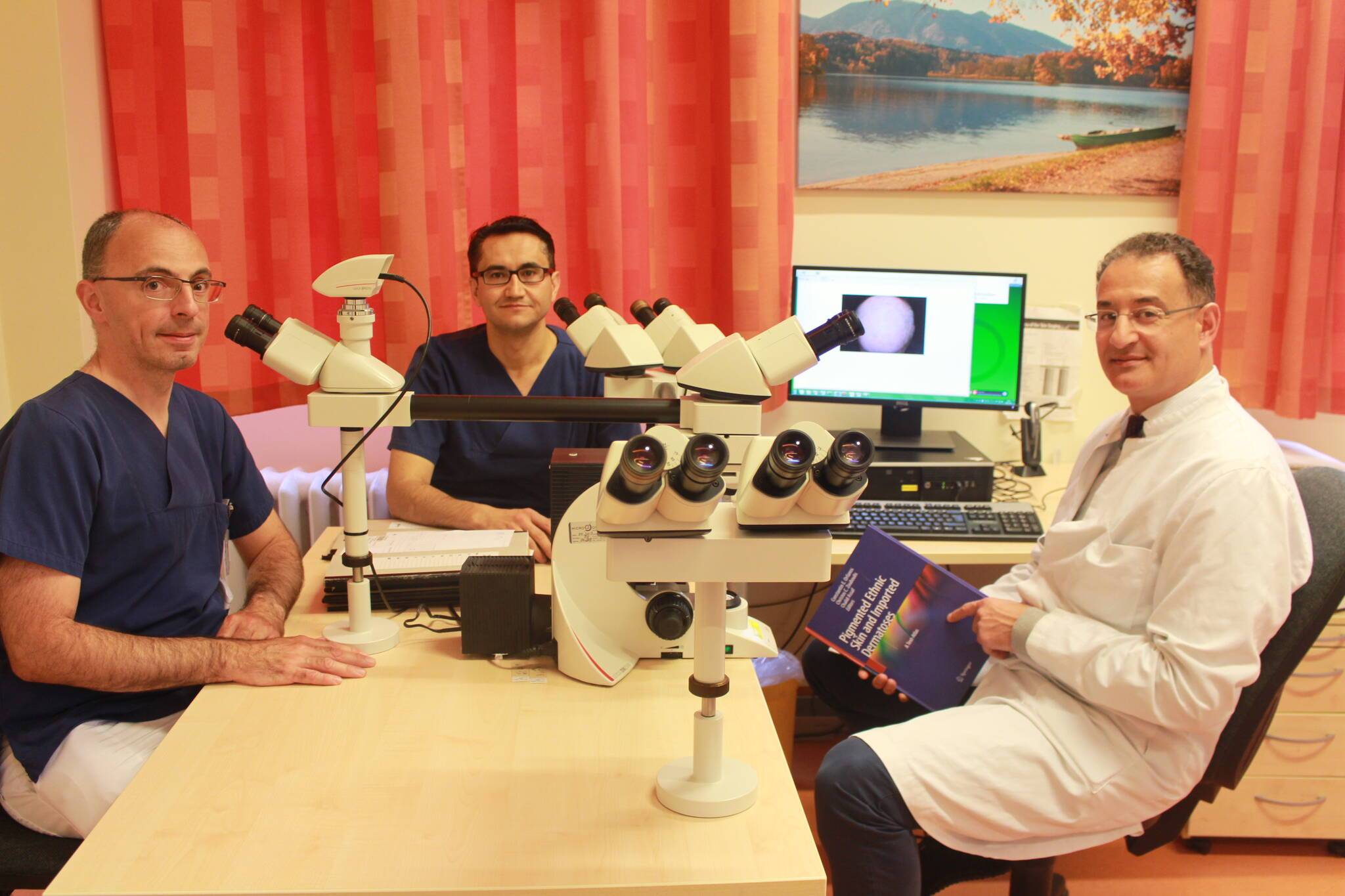 Chefarzt PD Dr. Chalid Assaf (r.), Oberarzt Dr. Frank Hessler (l.) sowie Oberarzt und Koordinator Dr. Mehmet Baltaci (Mitte) untersuchen mithilfe von Mikroskopen die Gewebeproben zur genaueren Bestimmung der Erkrankung. Die Ergebnisse werden auf dem Bildschirm digital dargestellt. Dr. Assaf vergleicht gerade die Untersuchungsergebnisse mit früheren Feststellungen, die er und internationale Kollegen in seinem neusten Fachbuch festgehalten und erläutert haben.