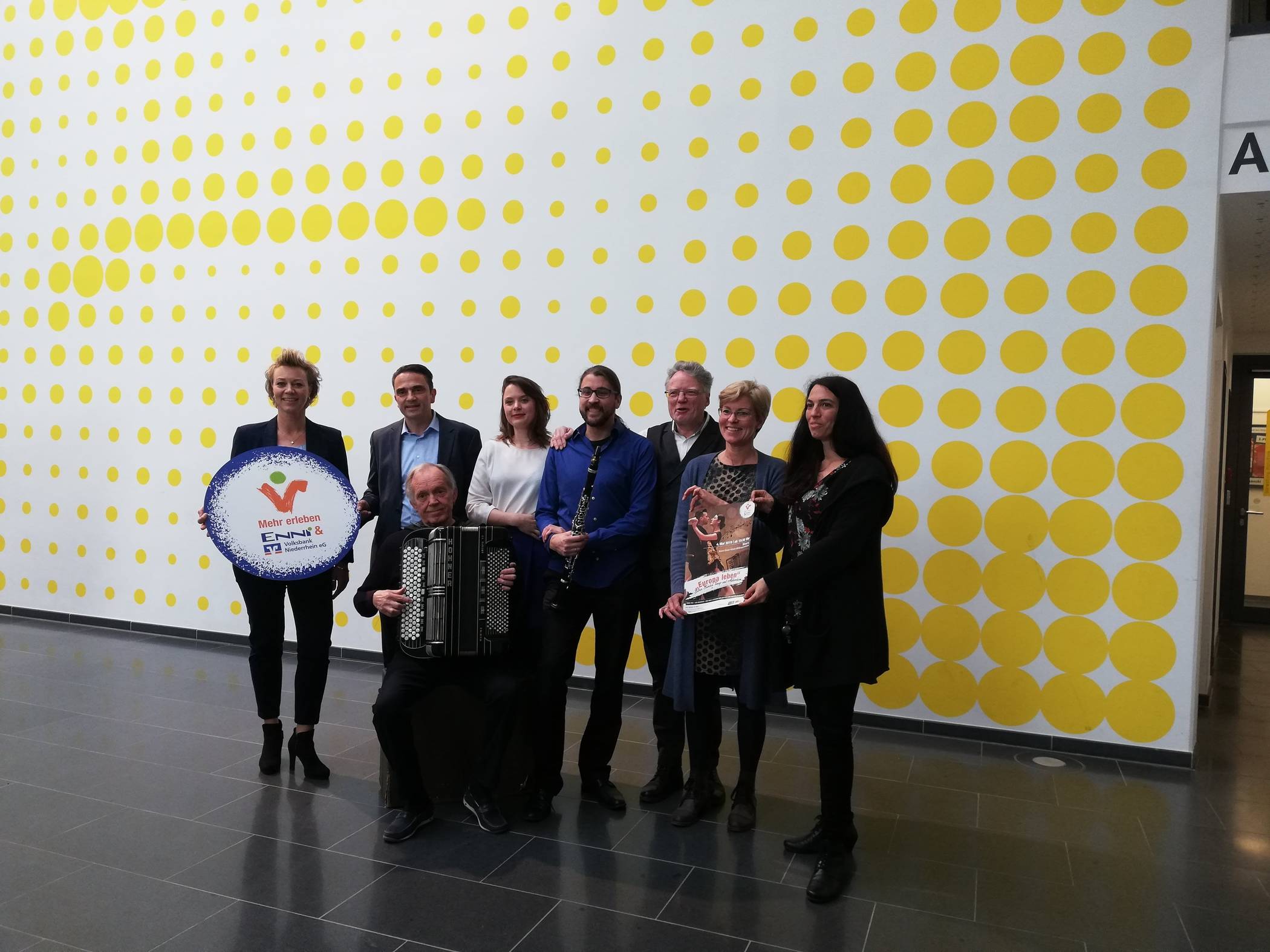 Stephanie Rieck (Pressesprecherin Volksbank Niederrhein eG), Herbert Hornung (Leiter der Abteilung Kommunikation ENNI), Fritz Schloss (Soloakkordeonist Werksorchester Bayer-Uerdingen), Stella-Louise Göke (Gesang) Robert Beck (Klarinette vom Ensemble FIRE, RAIN   ESPRESSO), Konrad Göke (künstlerische Leitung), Beate Schieren-Ohl (Hausherrin des Bildungszentrums der vhs) und Eva Marxen (Leiterin Kulturbüro der Stadt Moers) machen Werbung für Europa.