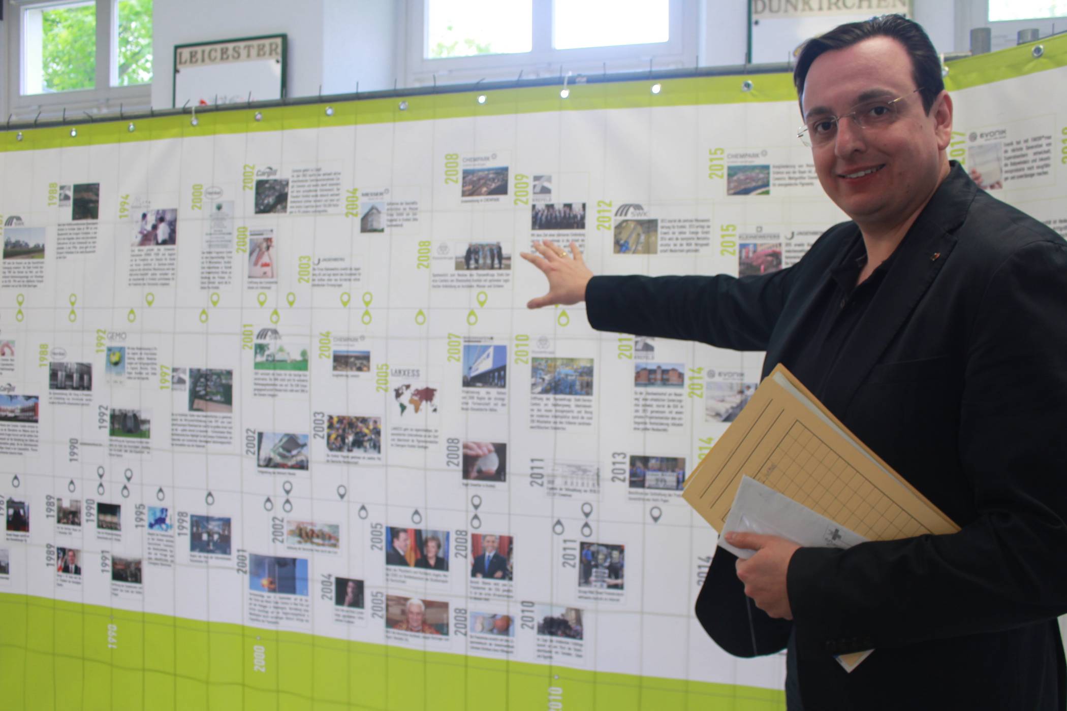  Übersicht: Die Ausstellung im Rathausfoyer lockt wissensdurstige Passanten an. Auch David Nowak aus dem Oberbürgermeisterbüro wirft beim Vorübergehen einen Blick auf die 12 Meter breite und mit vielen Bildern bestückte Stellwand. 