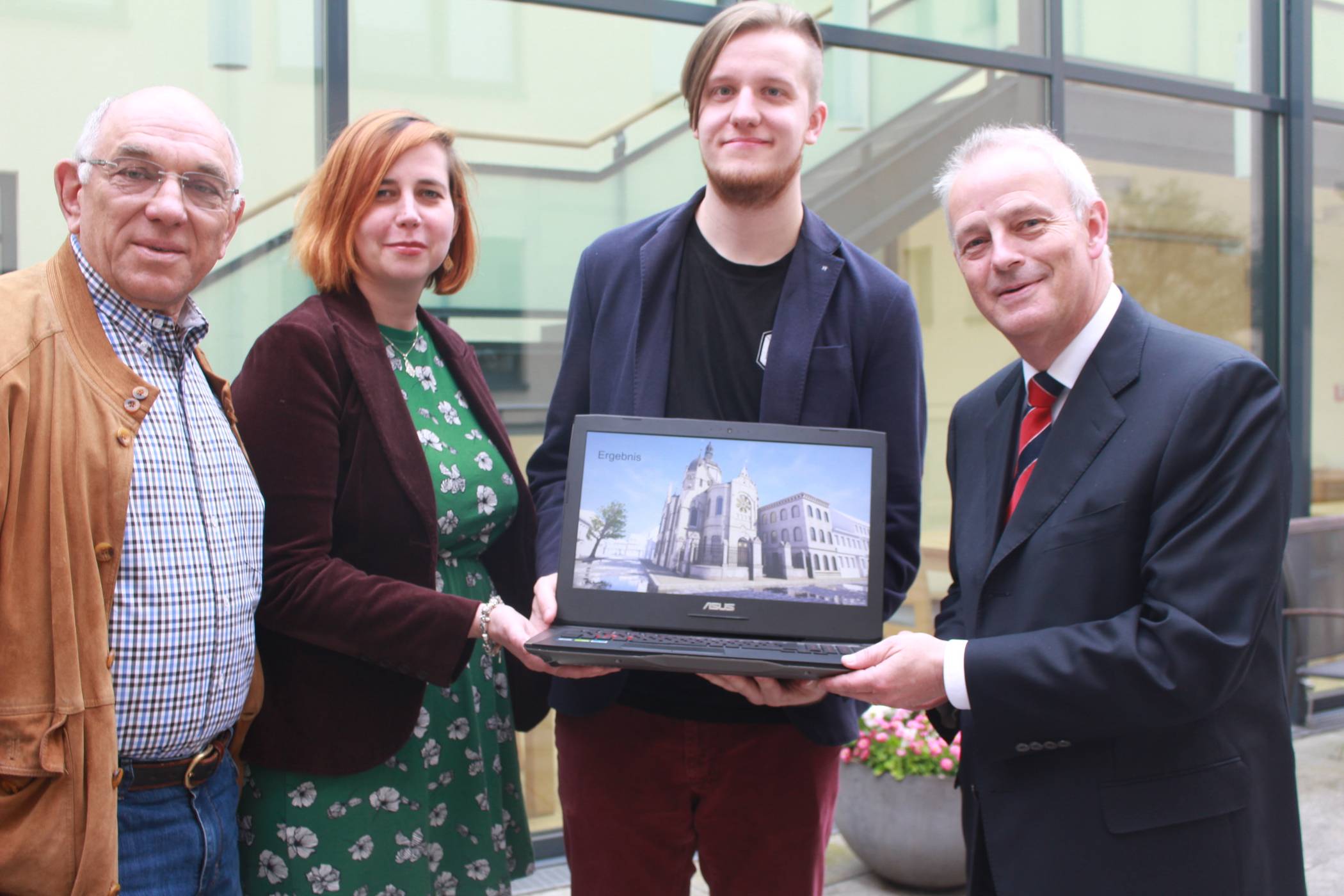 Freuen sich über das gute Ergebnis einer filigranen Computerarbeit: (v.l.) Michael Gilad, Vorsitzender der jüdischen Gemeinde; Sandra Franz, Leiterin der NS-Dokumentationsstelle Villa Merländer; Konstrukteur Lukas Kuhlendahl von den „Weltenwebern“ und Michael Rotthoff von der Kulturstiftung der Sparkasse. Auf dem Bildschirm erscheint die Animation der zerstörten Synagoge.