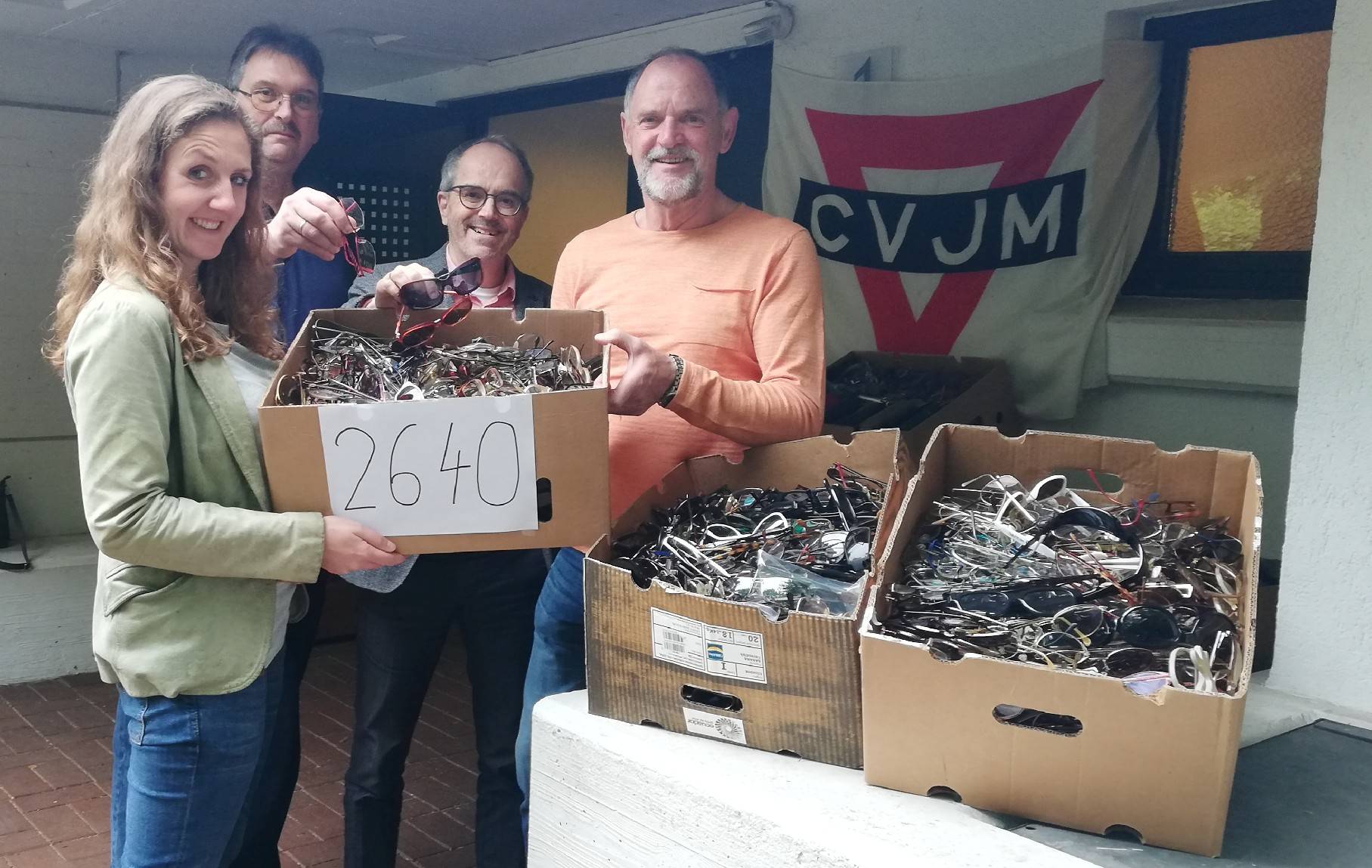 Simone Henzler (l) vom Deutschen Blindenhilfswerk freut sich über die 2.640 Brillen, die Horst Weien, stellvertretender Vorsitzender bei CVJM Moers-Hochstraß, Pfarrer Tobias von Boehn und Wolfgang Steinhardt (vl) am Gemeindezentrum überreichten.