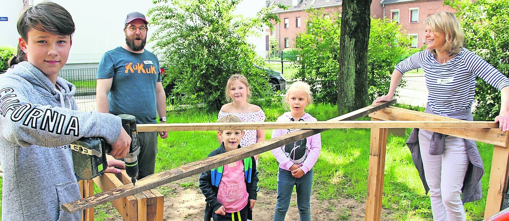 Anna Hardenberg (r.), bei der Stadt Meerbusch für die Planung von Spielplätzen zuständig, und David Zimmermann (2.v.l.) vom Planungsbüro „Kukuk“ packen gemeinsam mit den Kindern an, um den Spielplatz umzugestalten.