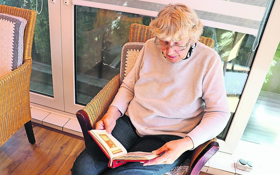 Elisabeth D. schaut sich das von ihr für ihre damalige Pflegetochter gestaltete Fotoalbum an