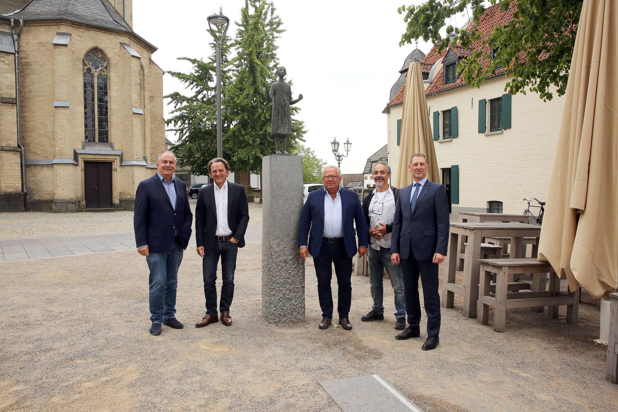   Dr. Gregor Bonin, Stadtdirektor und Technischer Beigeordneter (2. v. l.), präsentiert den neuen Edmund-Erlemann-Platz. Unterstützung gibt’s von den Anliegern/Sponsoren Michael Hollmann (Bolten/St. Vith, li.), Georg Walendy (Mitte) und Burkhard Wingerath (Sparkasse, r.). Den Sockel für die Vitus-Skulptur hat Steinbildhauer Werner Jacobs (2. v. r.) entworfen. 