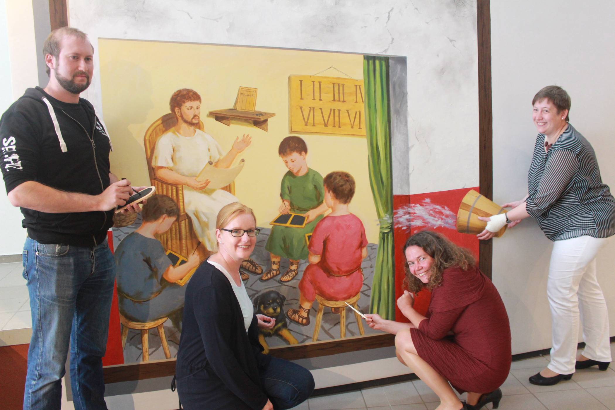 Auf spielerische Weise führen Museumsdirektorin Dr. Jennifer Morscheiser (2.v.r.), Lehrerin Vera Lange (r.), Workshop-Leiterin Petra Kornfeld-Möller (l.) und Spieleleiter Eric Sponville den jungen Besuchern vor, wie Schule im alten Rom funktionierte.