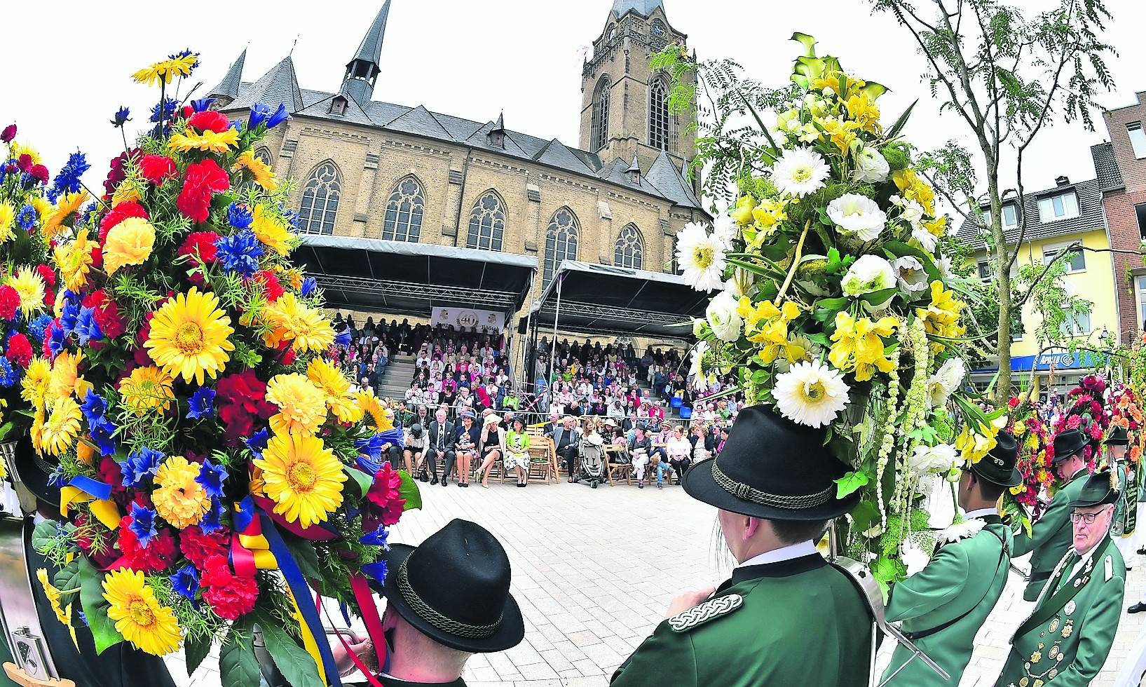 Ein Blick durch zwei schön gestaltete Blumenhörner auf die neue überdachte Tribüne vor St. Katharina.