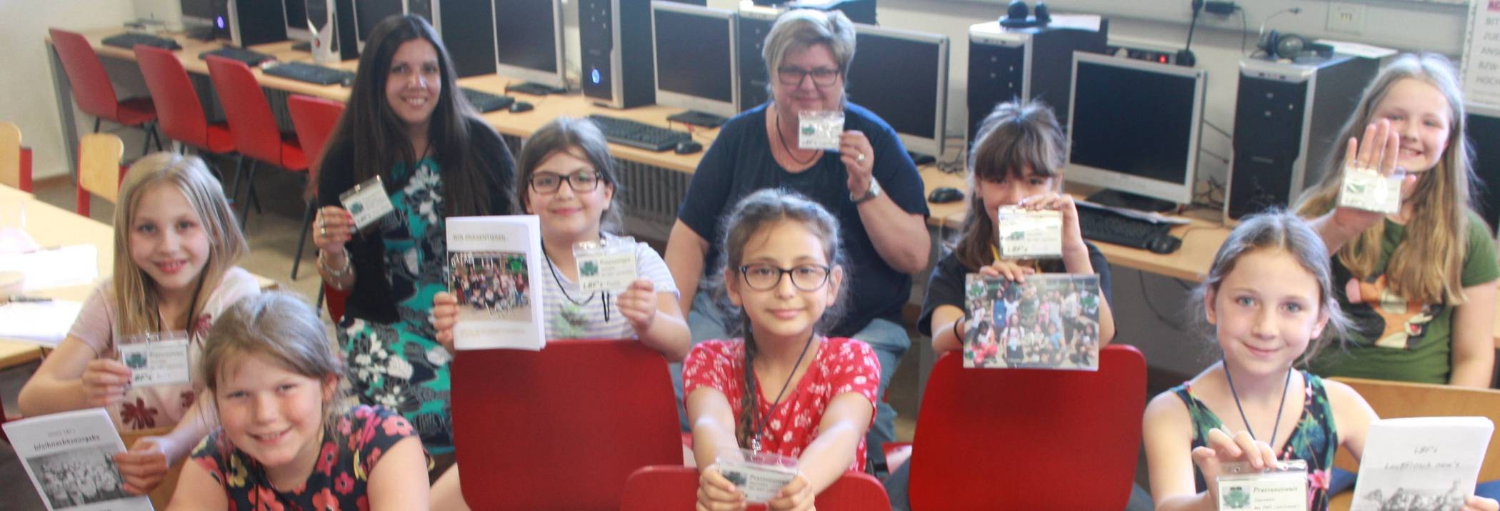 Die Redaktion der Schülerzeitung Laubfrosch: (v.l. vorne): Lucy, Maria und Isabell; (v.l. zweite Reihe): Aurora, Tuana, Olivia und Alicée; sowie die Erzieherinnen (v.l.) Jessica Pinau und Gudrun Klauth. Die jungen Redakteurinnen zeigen stolz ihre schön gestalteten Presseausweise und Ausgaben ihrer Zeitung vor.