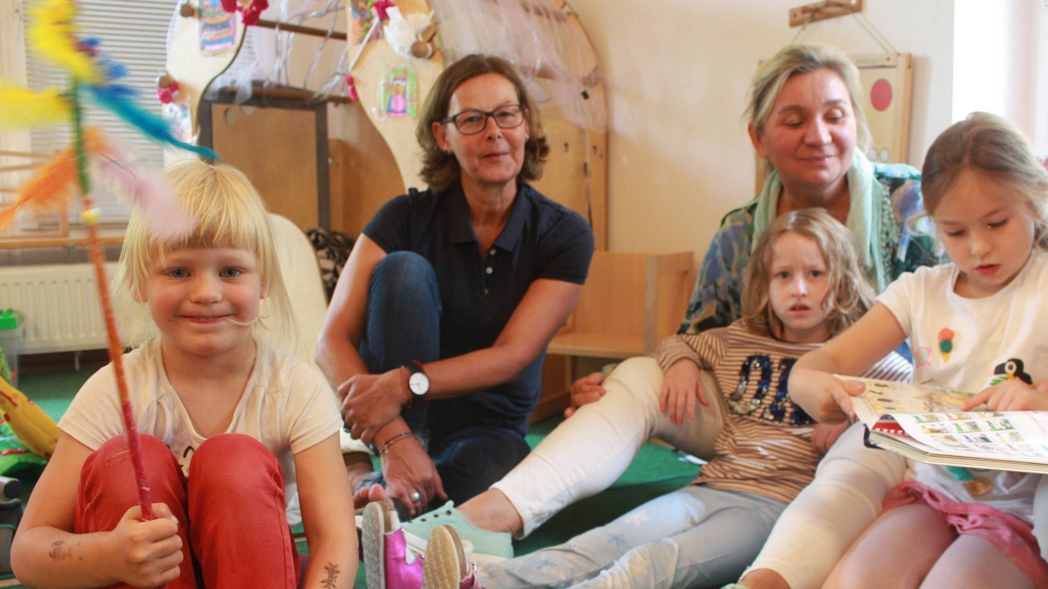  Rederecht: Wer den Stab in Händen hält, darf ungestört sprechen. Leonie (l.) hat ihre Meinung gerade kund getan. Louisa (r.) zeigt dem Besucher im Buch das Märchen, um das sich das Gespräch dreht. Erzieherin Dana Majster (r.) kuschelt derweil mit Lilly und Kita-Leiterin Iris Stachelhaus leitet die Gesprächsrunde an. Es geht zugleich konzentriert und entspannt zu beim Kinderparlament. 