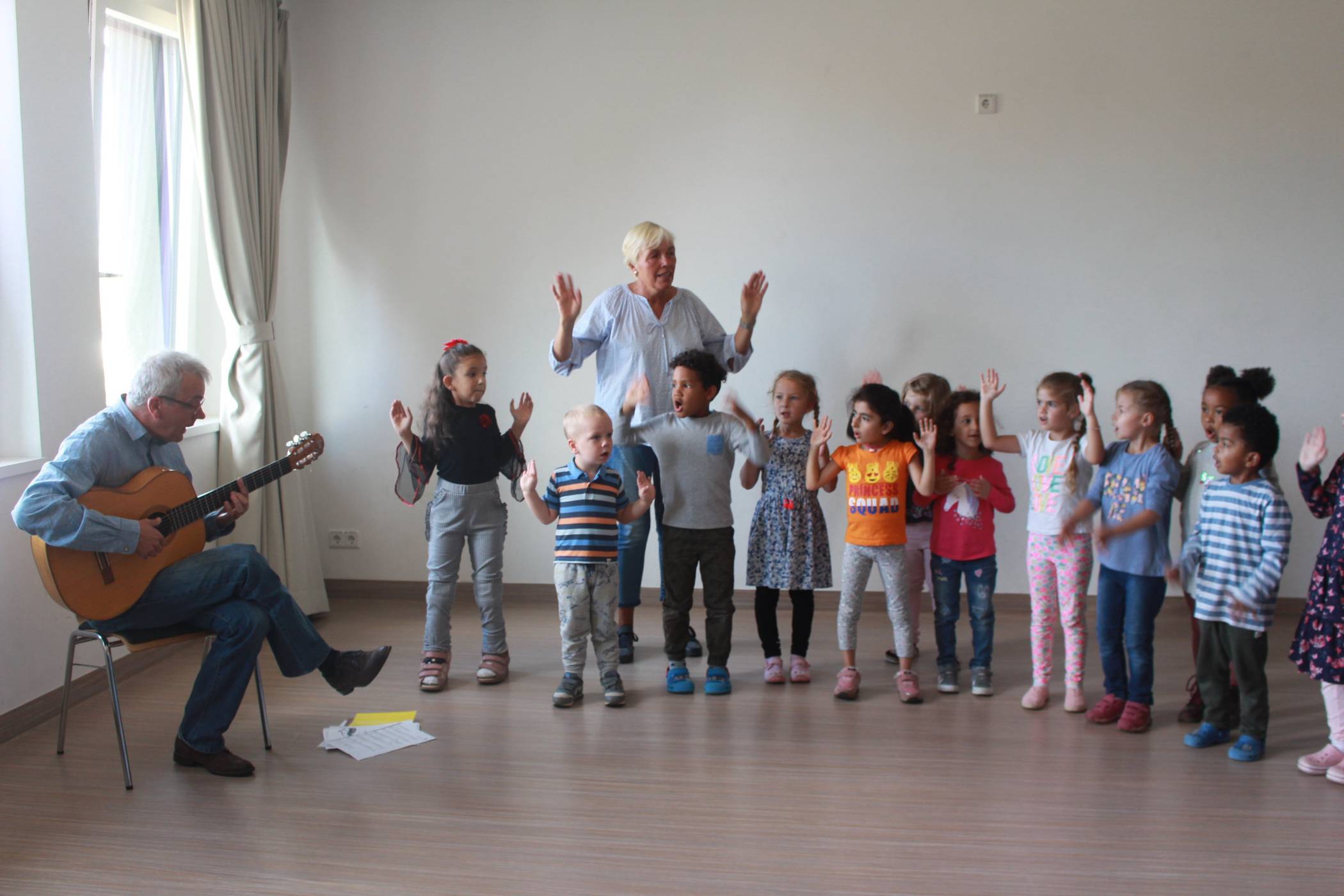  Mund auf und Arme hoch: Thorsten Drees begleitet die Kinder des Familienzentrums Westwall mit seiner Gitarre beim Singen. 