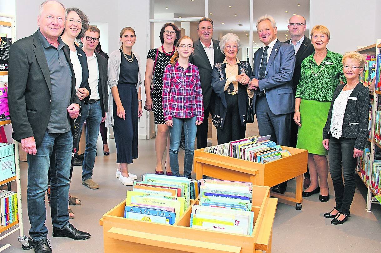 Architekt Jürgen Oberdörfer (l.), das Büchereiteam unter Leitung von Katrin Hufschmidt (2.v.l.), die Dezernenten Brigitte Schwerdtfeger und Willy Kerbusch (Mitte Hintergrund) sowie Bürgermeister Josef Heyes (4.v.r.) mit Irmgard Tillmanns bei der Eröffnung.