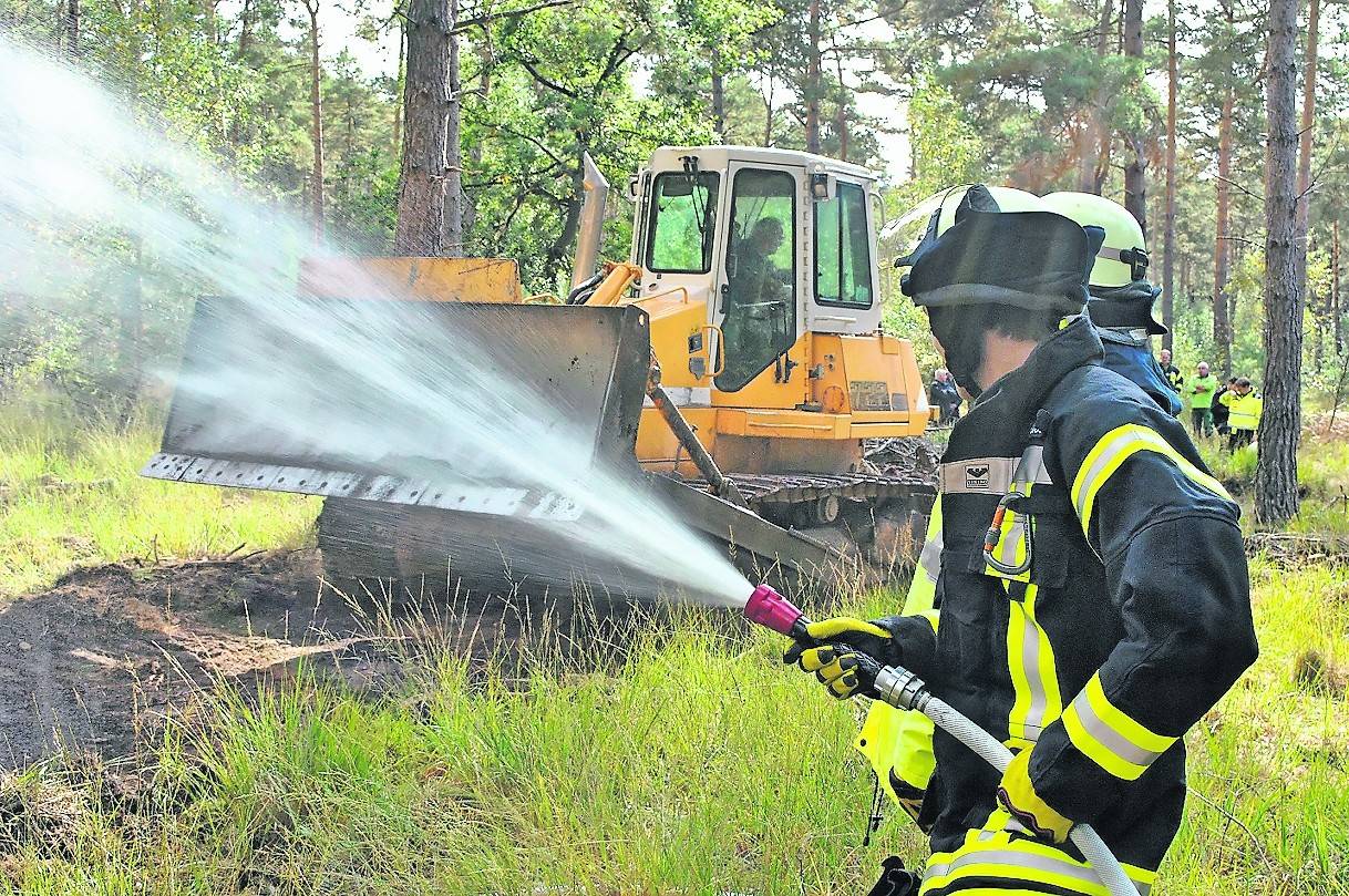  Ein Bulldozer schiebt eine Schneise durch das Unterholz. Um ein Übertreten des Brandes zu verhindern, wird die Schneise gewässert. 