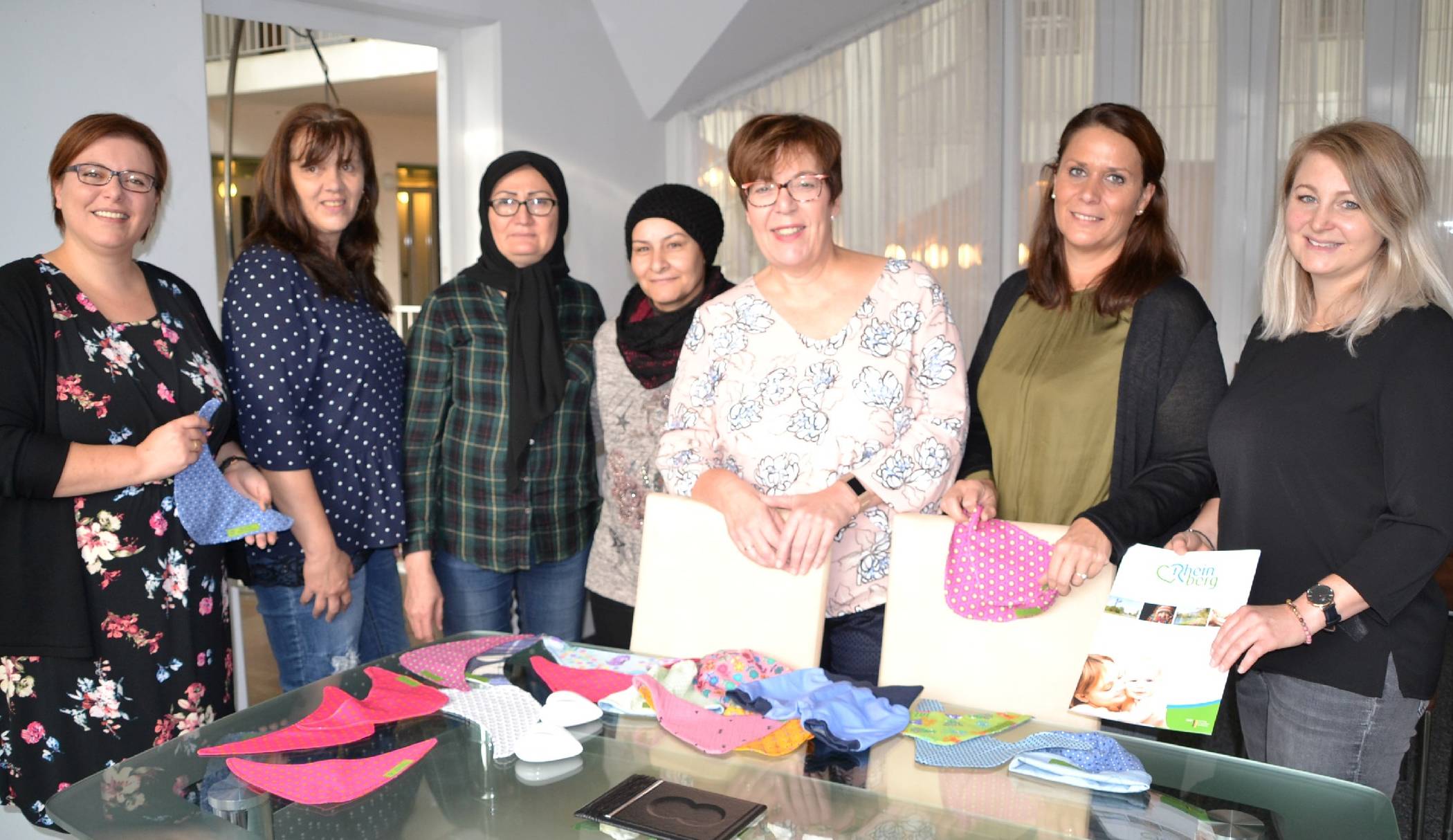 Sarah Bernstein, Birgit Kraemer, Mahrach Aslampur, Seham Mohammed, Rosemarie Kaltenbach, Michaela Bothen und Maike Holthuis (v. l.) stellen das Beratungsangebot „Frühe Hilfen“ in Rheinberg vor, im Rahmen dessen die Willkommenspakete für Neugeborene verteilt werden - mit vielen Informationen, aber auch niedlichen Geschenken.