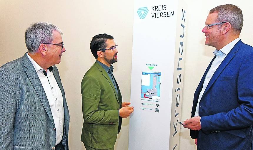 Maaged Mazyek (Mitte), Gründer von WEGZWEI, stellt Landrat Dr. Andreas Coenen (r.) und Bruno Wesch, Leiter des Gebäudemanagements Kreis Viersen, die digitale Navigation durch das Kreishaus vor. Die Infosäule befindet sich im Wartebereich des Gesundheitsamtes, Eingang 4.