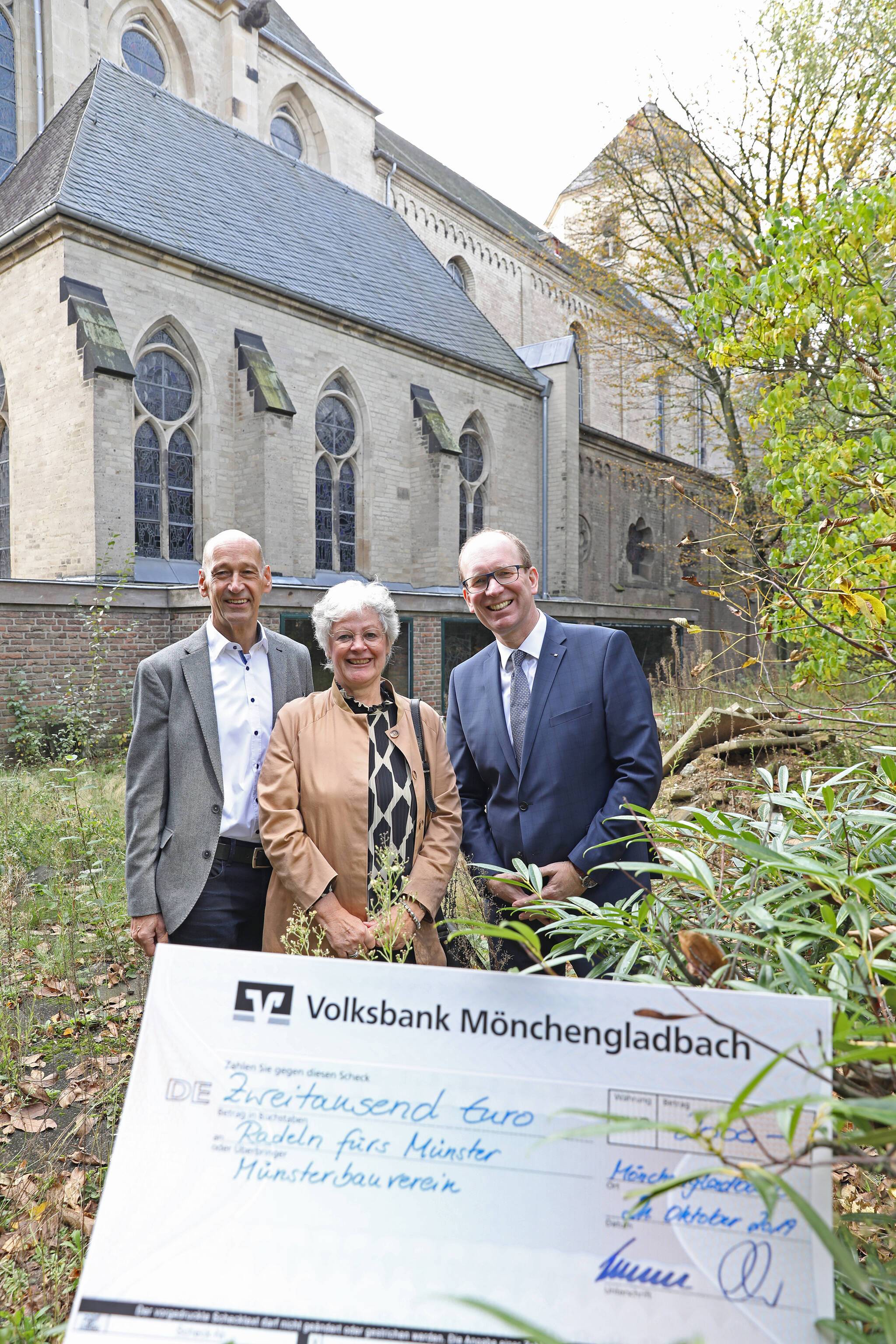  Johann Konder (l.) vom Radsportbezirk Mönchengladbach und Franz Dierk Meurers (r.), Vorstand der Volksbank Mönchengladbach, überreichten den Scheck über 2000 Euro an Anne Baus vom Münsterbauverein. 