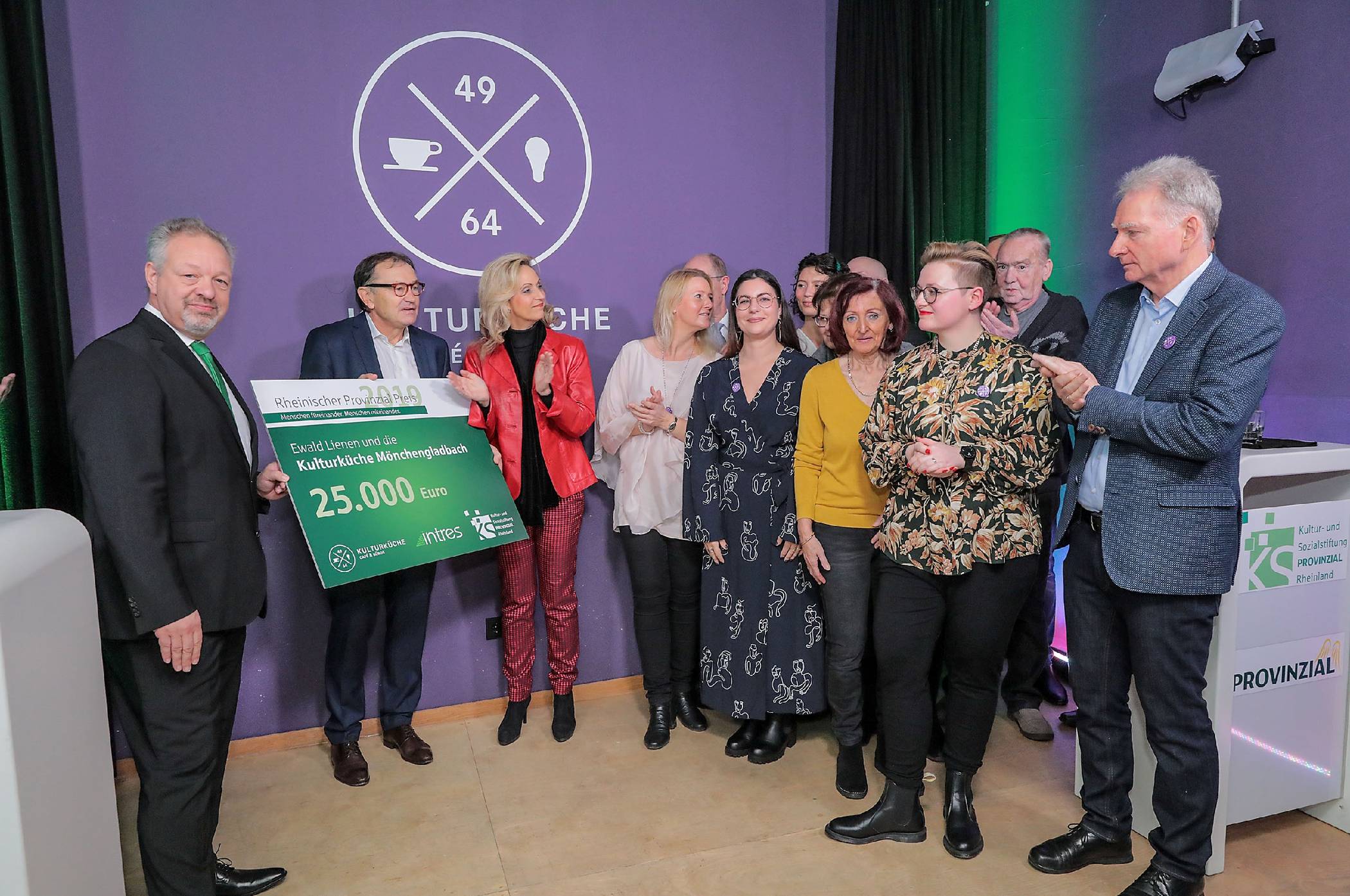  „Pate“ Ewald Lienen (2.v.l.), Patric Fedlmeier, Vorstandsvorsitzender der Provinzial Rheinland (l.) und Ulrike Lubek (3.v.l.), Direktorin des Landschaftsverbandes Rheinland, überreichen den mit 25000 Euro dotierten Scheck an das Team der Kulturküche mit Hannah und Norbert von Dahlen (vorne r.). 
