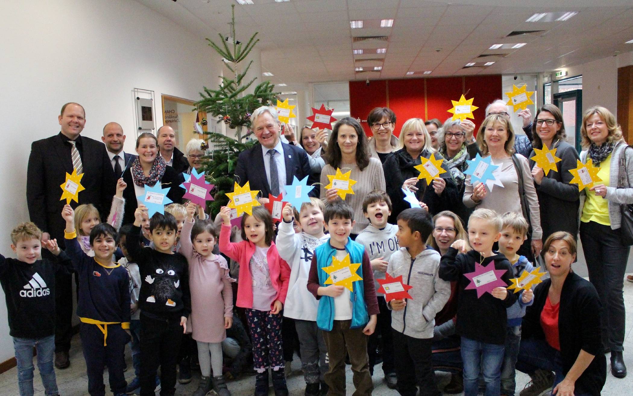 In der Sparkasse in Alt-Willich haben Kinder und der Bürgermeister die ersten Wunschsterne an den Weihnachtsbaum gehangen.