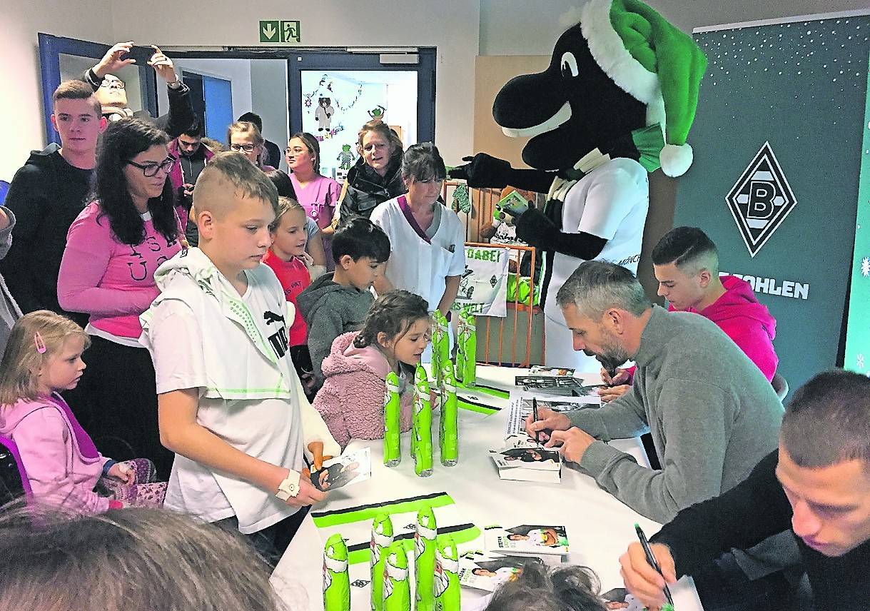Schreiben Autogramme für die kleinen Patienten der Eli-Kinderklinik: Stefan Lainer, Marco Rose und Lászlo Bénes (r. v. u. n. o.). Links: Prof. Dr. Wolfgang Kölfen zeigt sein neues Trikot.