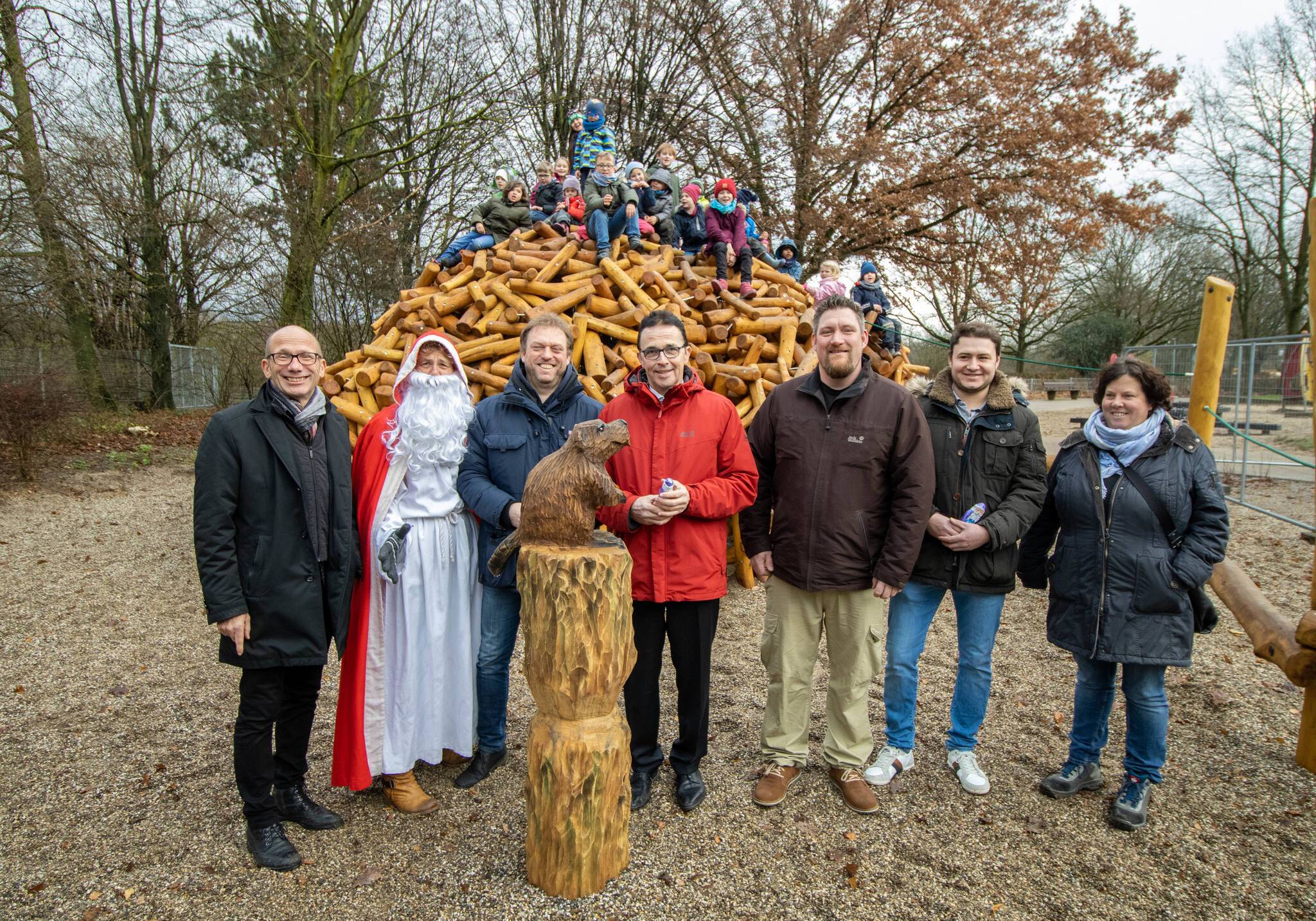 Jugenddezernent Dr. Christoph Müllmann, Nikolaus, Martin Richardt (dtp Landschaftsarchitekten), Bürgermeister Prof. Dr. Christoph Landscheidt, Mike Oberhäuser (Naturholzdesign am Niederrhein), Sven Flohrack (Naturholzdesign am Niederrhein), Nicole Lohbeck (Grünflächenamt) mit Kindern der Grundschule am Pappelsee und der Kita Tausendfüßler auf der Biberburg.