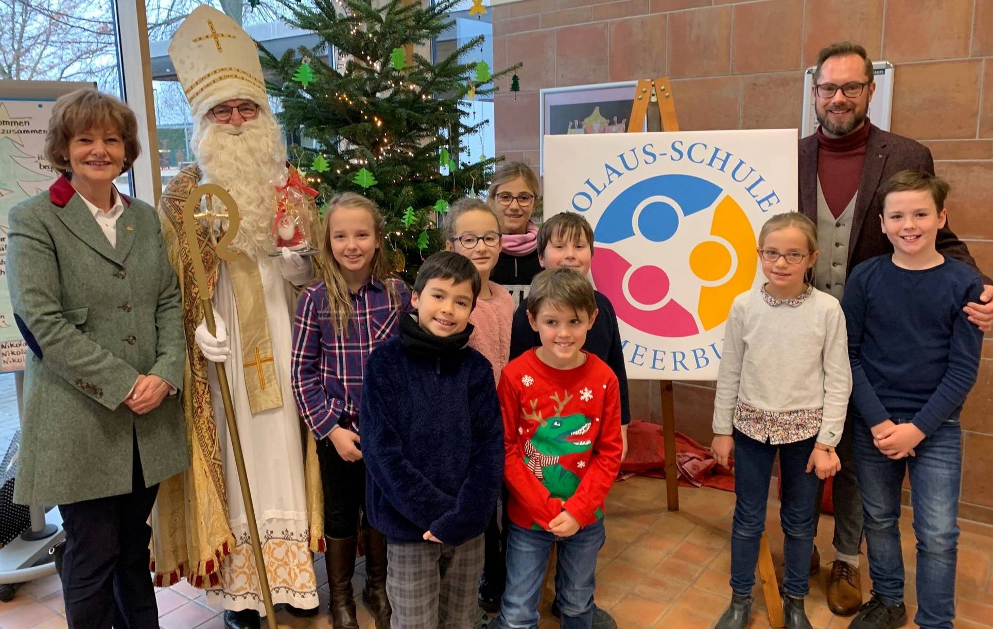 Bürgermeisterin Mielke-Westerlage, „Nikolaus“ Franz-Josef Moormann, die Klassensprecher der Schule und Schulleiter Marcus Niemann präsentieren das neue Schullogo.