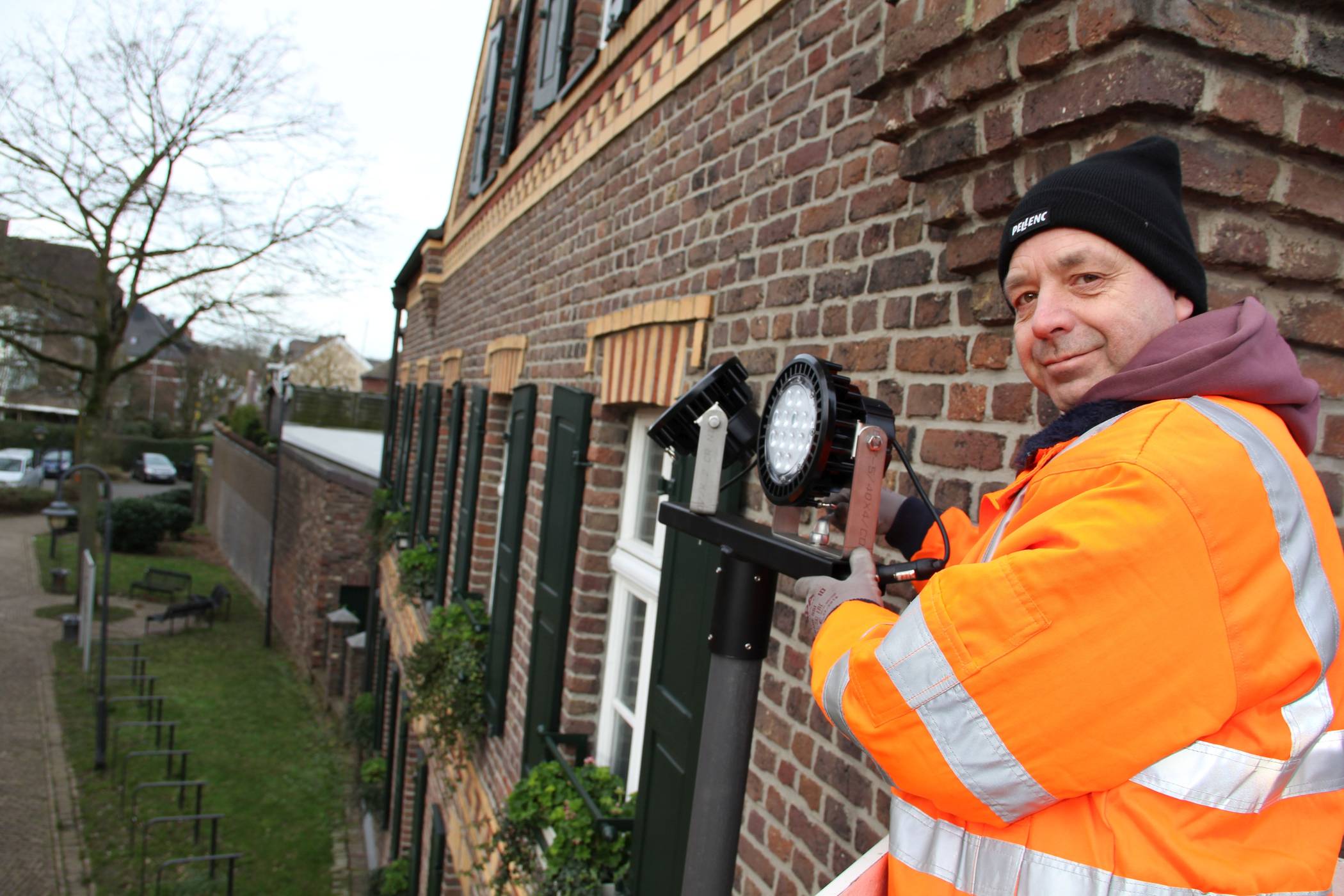 Ralf Knur montiert die neue Leuchte unmittelbar neben dem historischen Fronhof in Lank.