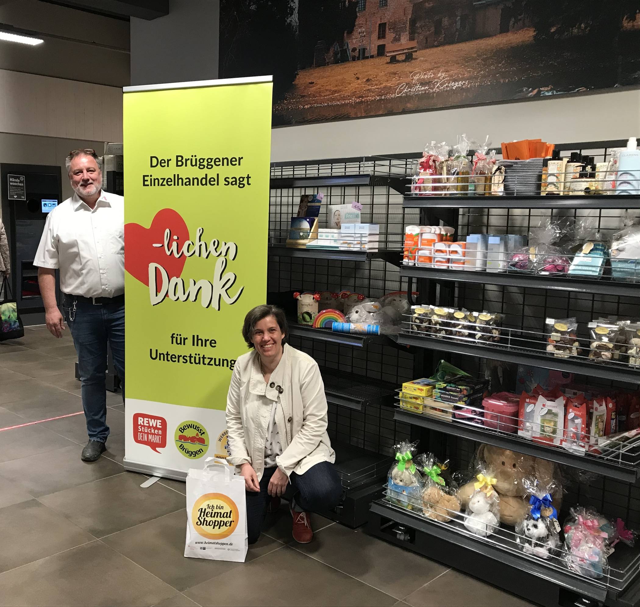 Ralf Stücken (REWE Stücken) und Claudia Holthausen (Werbering Brüggen) vor dem neu eingerichteten Regal mit Produkten des Brüggener Einzelhandels.