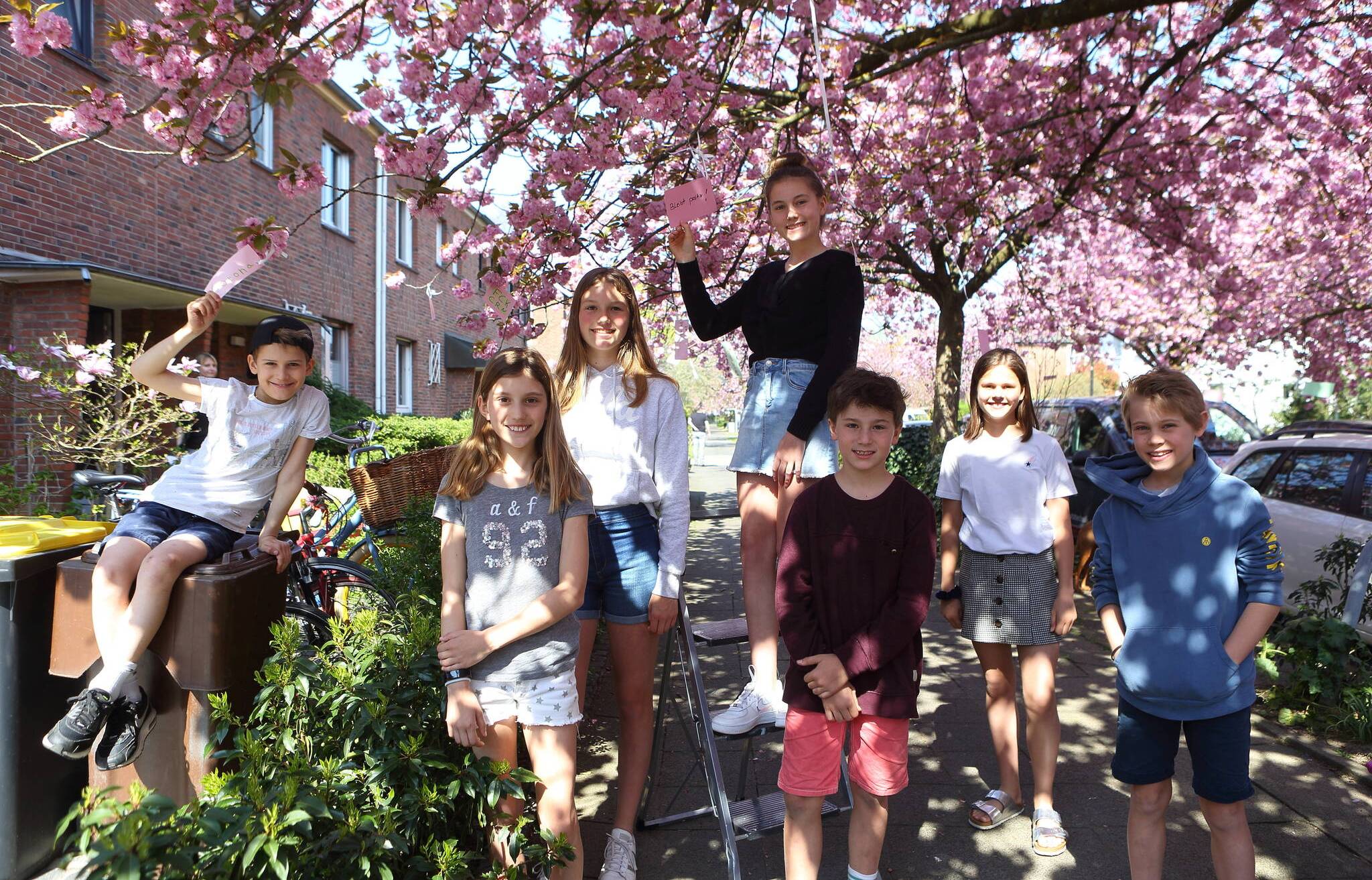 Kinder hängen Wünsche an Kirschbäume