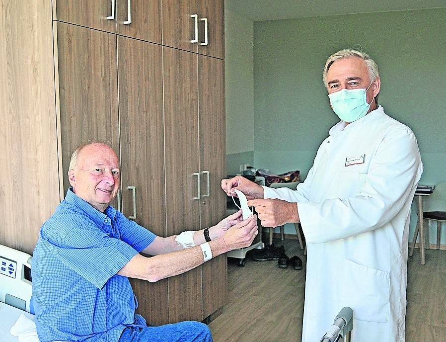 Prof. Dinko Berkovic überreicht den Mundschutz an Bernhard Hoff. Neben der Abstandsregelung ist der Mundschutz Teil des Sicherheitskonzepts.